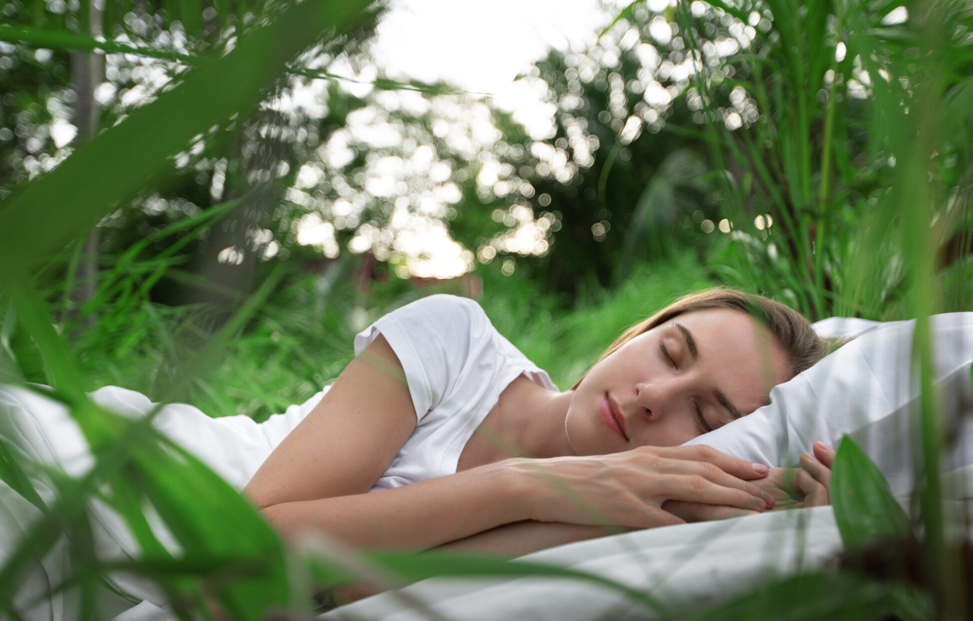 Woman sleeping on grass while listening to nature