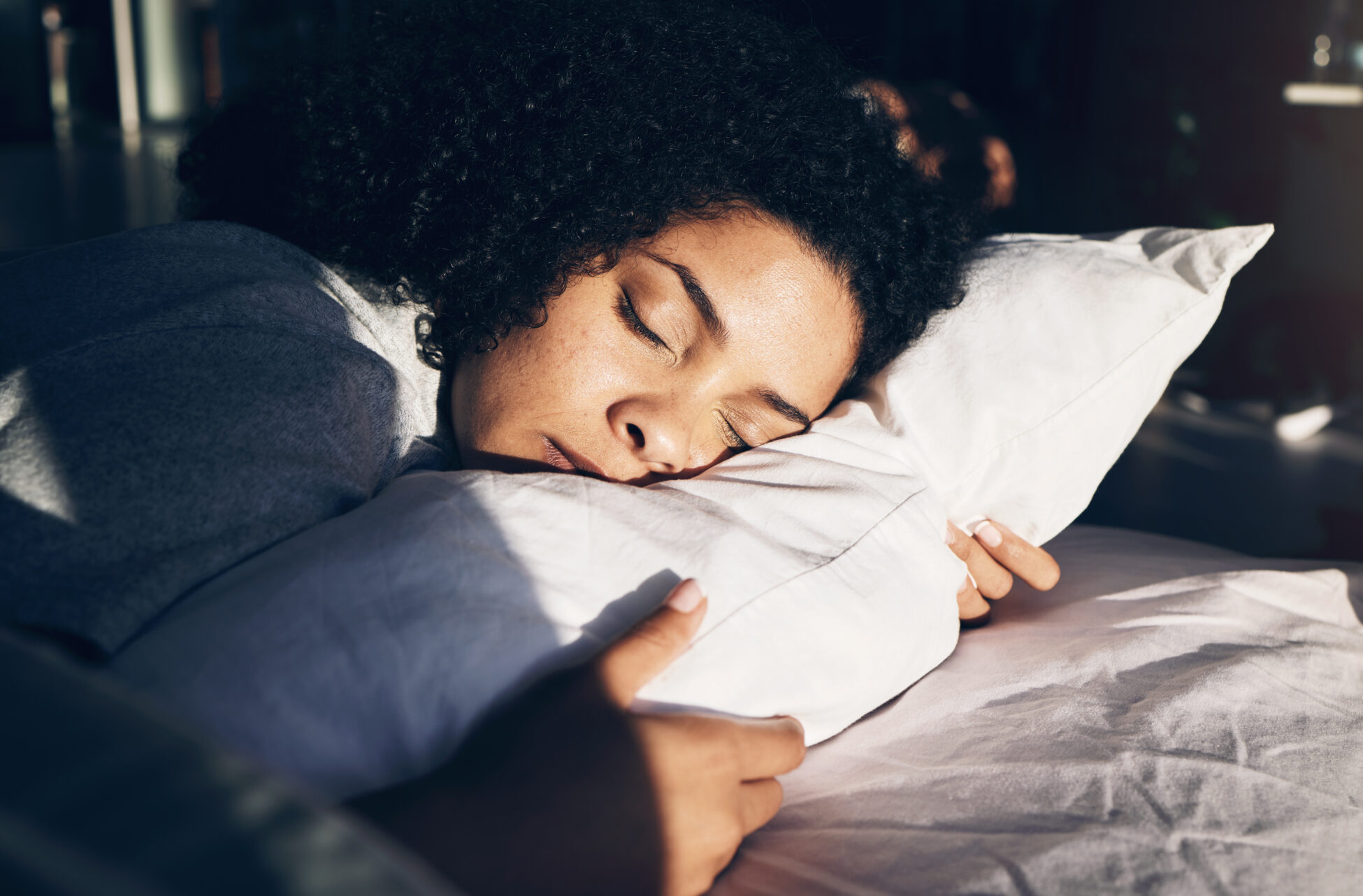 Young woman sleeping on soft pillow in her bed while the sun rises